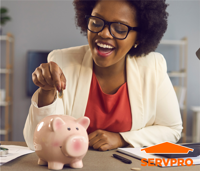 A woman happily putting some coins in a piggy-bank. 